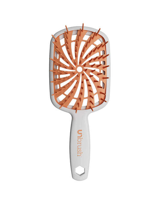 White Unbrush Plus detangling brush with orange spiral bristle pattern, designed for gentle use on wet or dry hair.